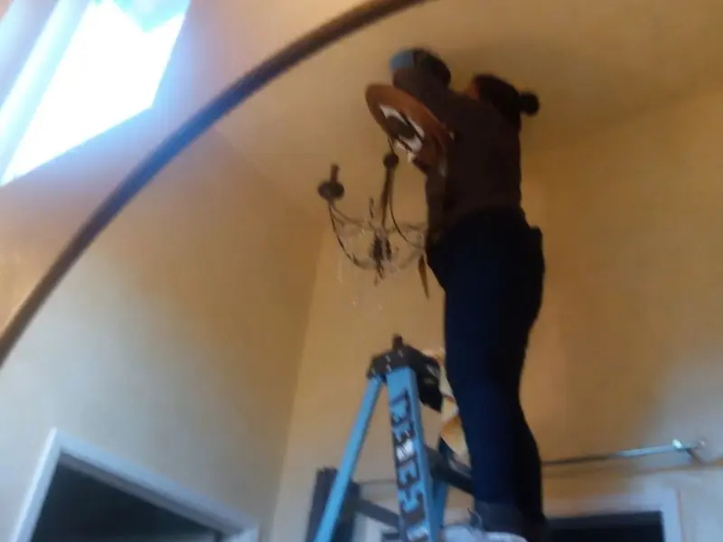 Electrician installing a chandelier in a Addison residence